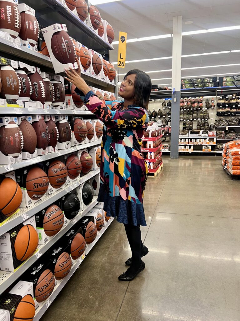 Black woman shopping for a football at Walmart in article for financial reset after the holidays for single moms.