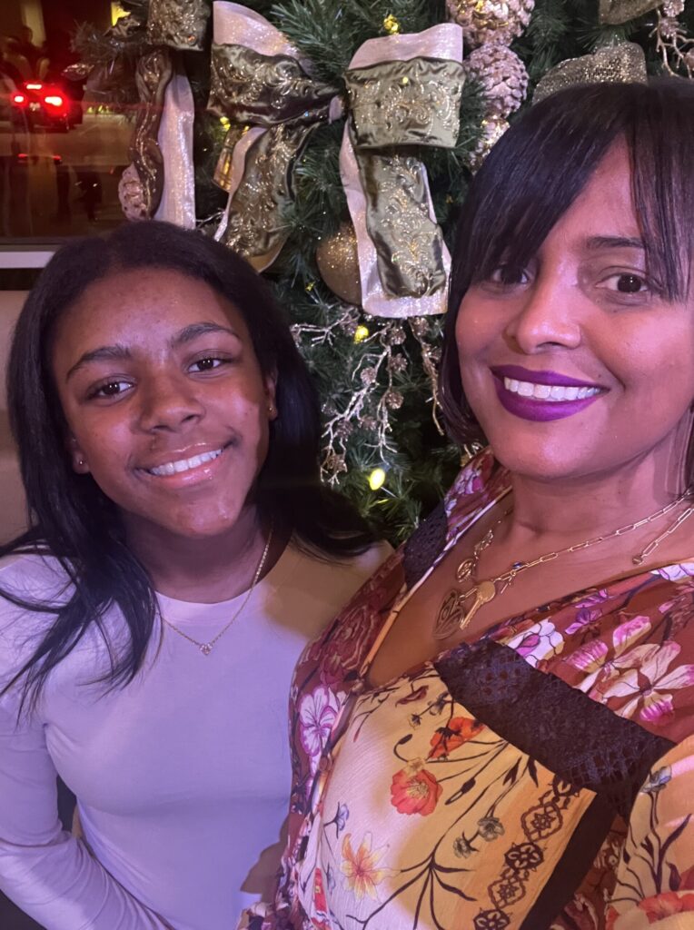 Mother and daughter smiling in front of a Christmas tree in article for financial reset after the holidays for single moms.